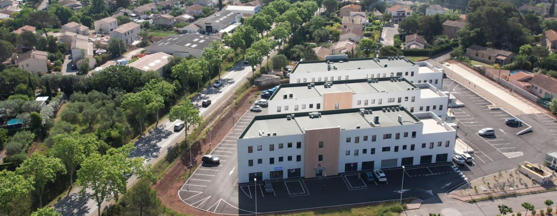 trois bâtiments blanc et ocre au milieu d'un espace mi rural mi urbain