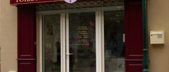 devanture de magasin rouge pourpre avec informations pratiques sur la boutique écrites dessus.