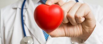 médecin tenant un coeur en plastique dans la main.