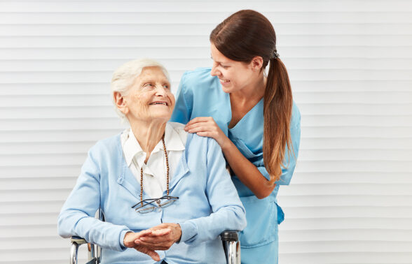 une infirmière souriante parle avec une personne âgée assise sur une chaise - Agrandir l'image, fenêtre modale
