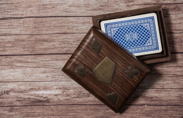 Table en bois sur laquelle est disposée une boîte, à l'intérieur de laquelle l'on voit un jeu de cartes bleu et blanc - Agrandir l'image, fenêtre modale