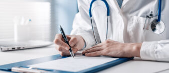 médecin assis à son bureau rédige une prescription sur ordonnance.