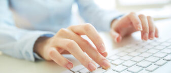 des mains pianotent sur le clavier d'un ordinateur
