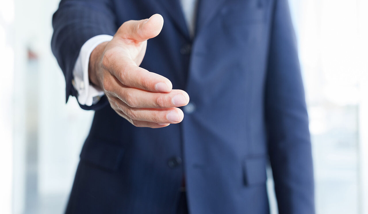 homme en costume tend la main