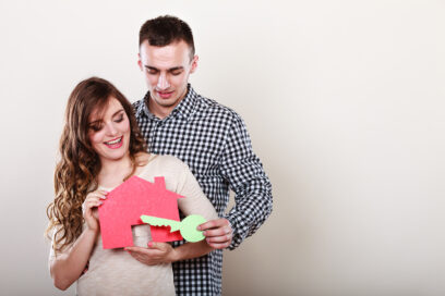 un homme et une femme enlacés tiennent une maquette de maison dans leurs bras - Agrandir l'image, fenêtre modale