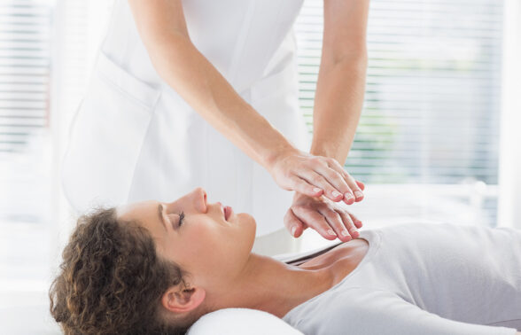 une femme allongée sur le dos se laisse faire pendant qu'un praticien pratique le magnétisme - Agrandir l'image, fenêtre modale